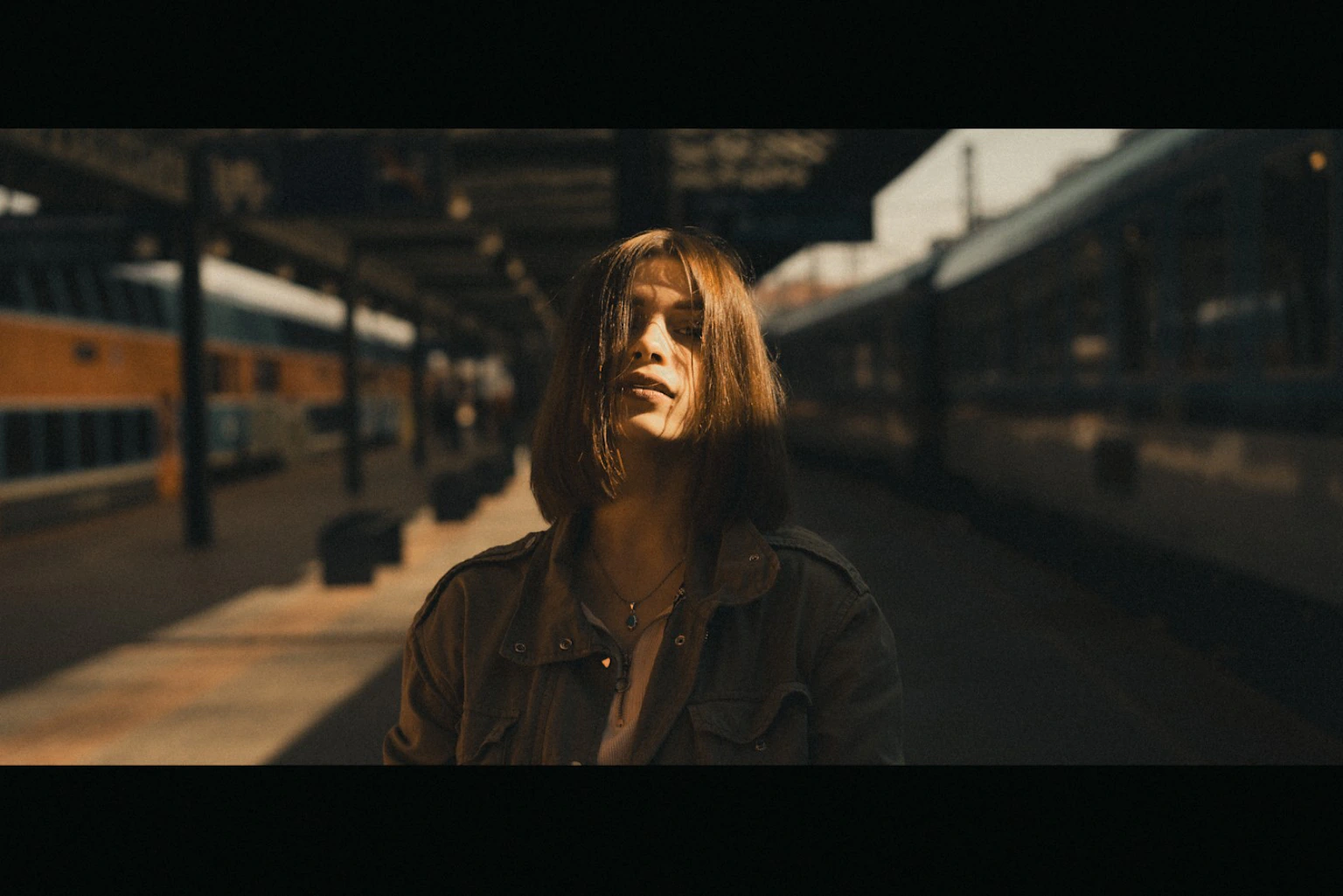 Woman standing in warm sunlight on a railway platform