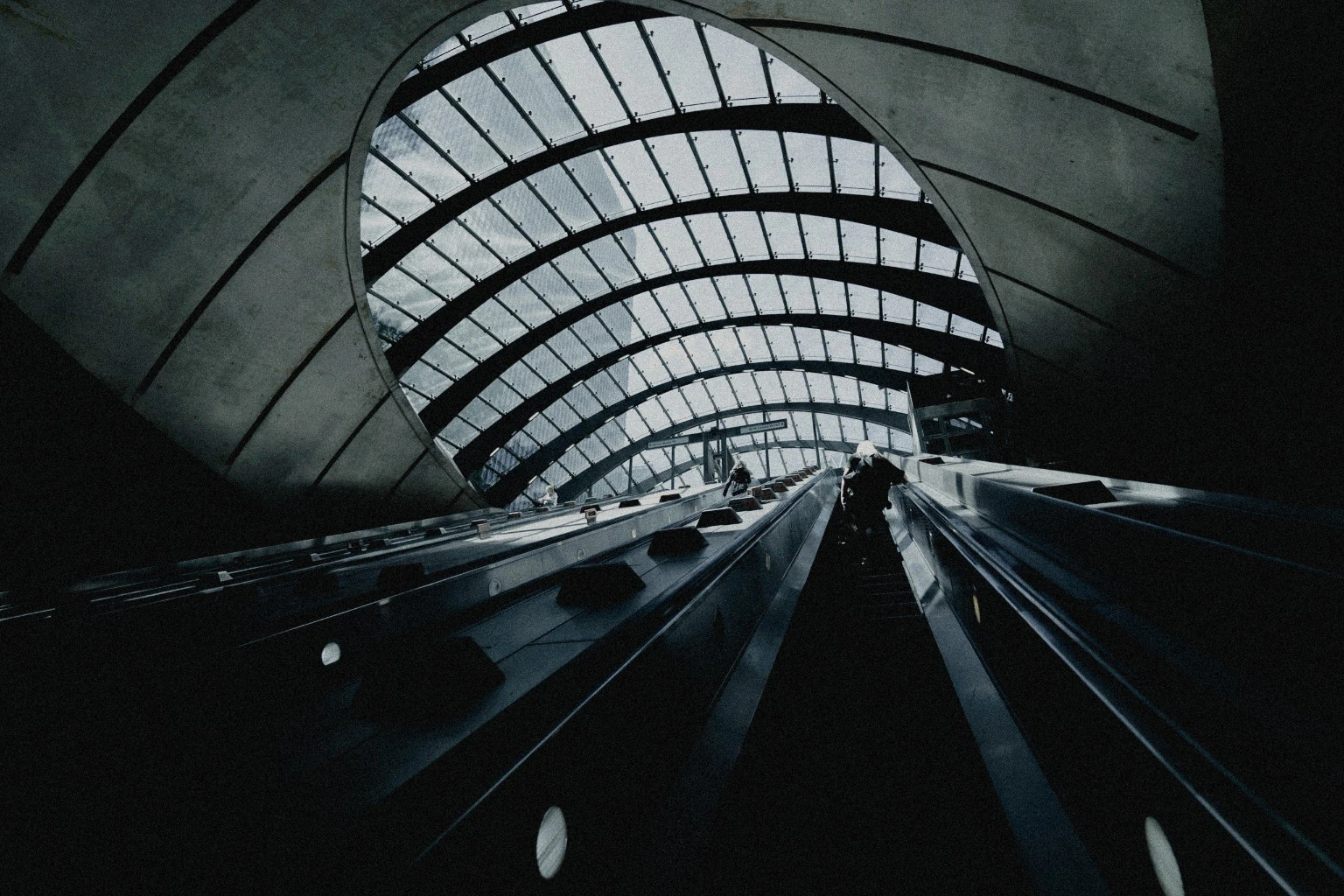Escalators beneath a sweeping glass canopy