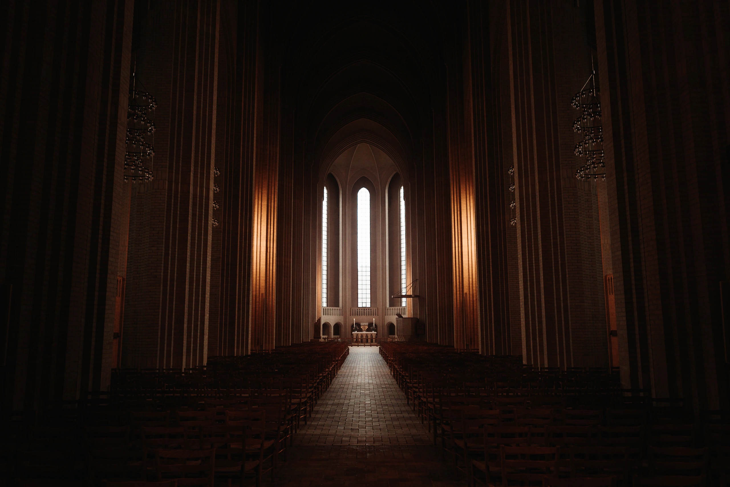 The central aisle of Grundtvig's Church leading through warm brick arches to tall white windows