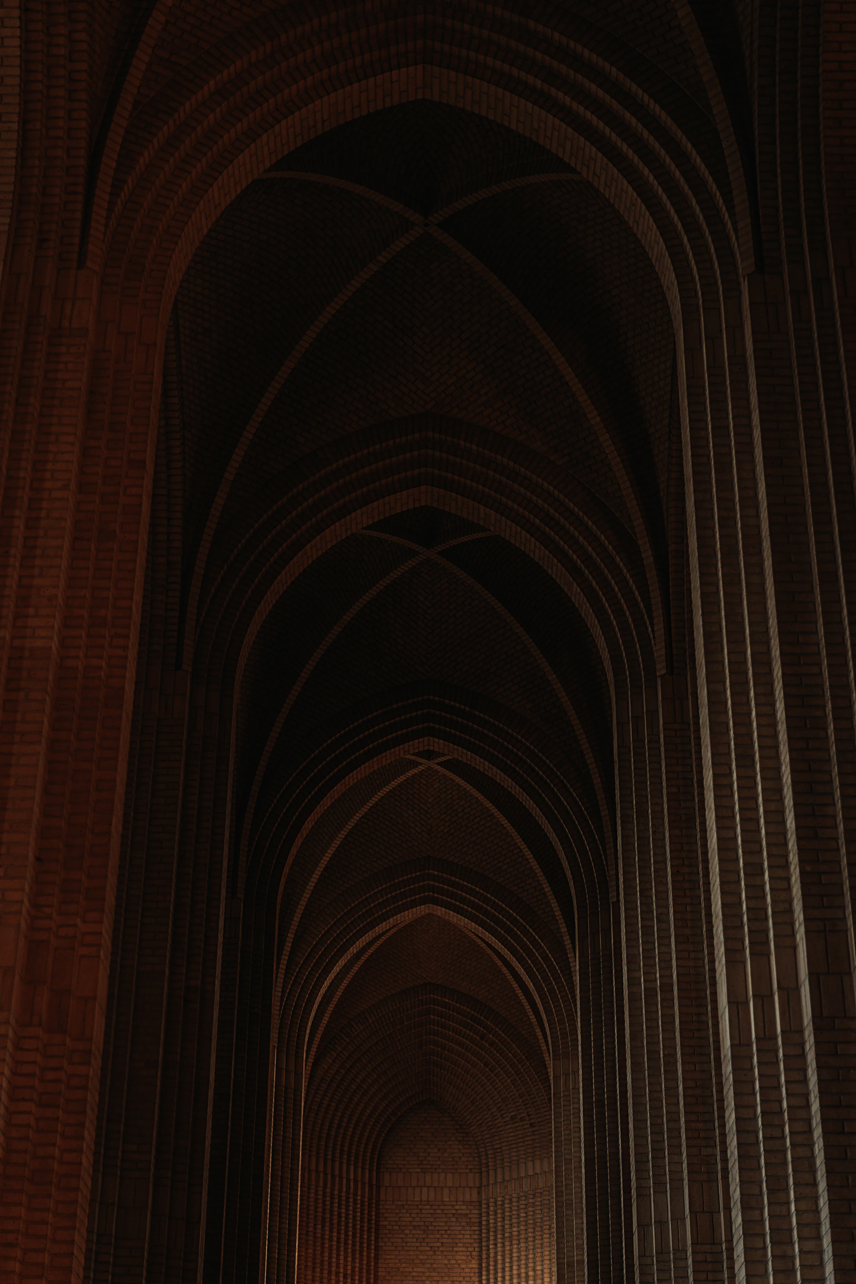 Repeating pointed brick vaults rising into the darkness of the church ceiling