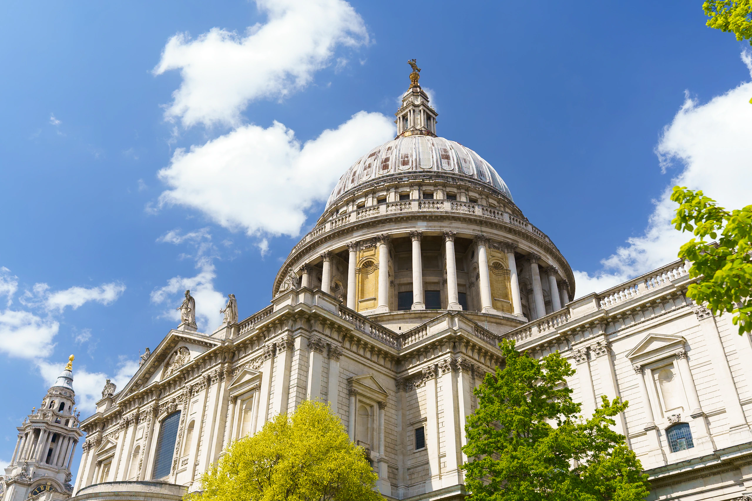 The dome of St Paul's Cathedral beneath bright blue sky and white clouds