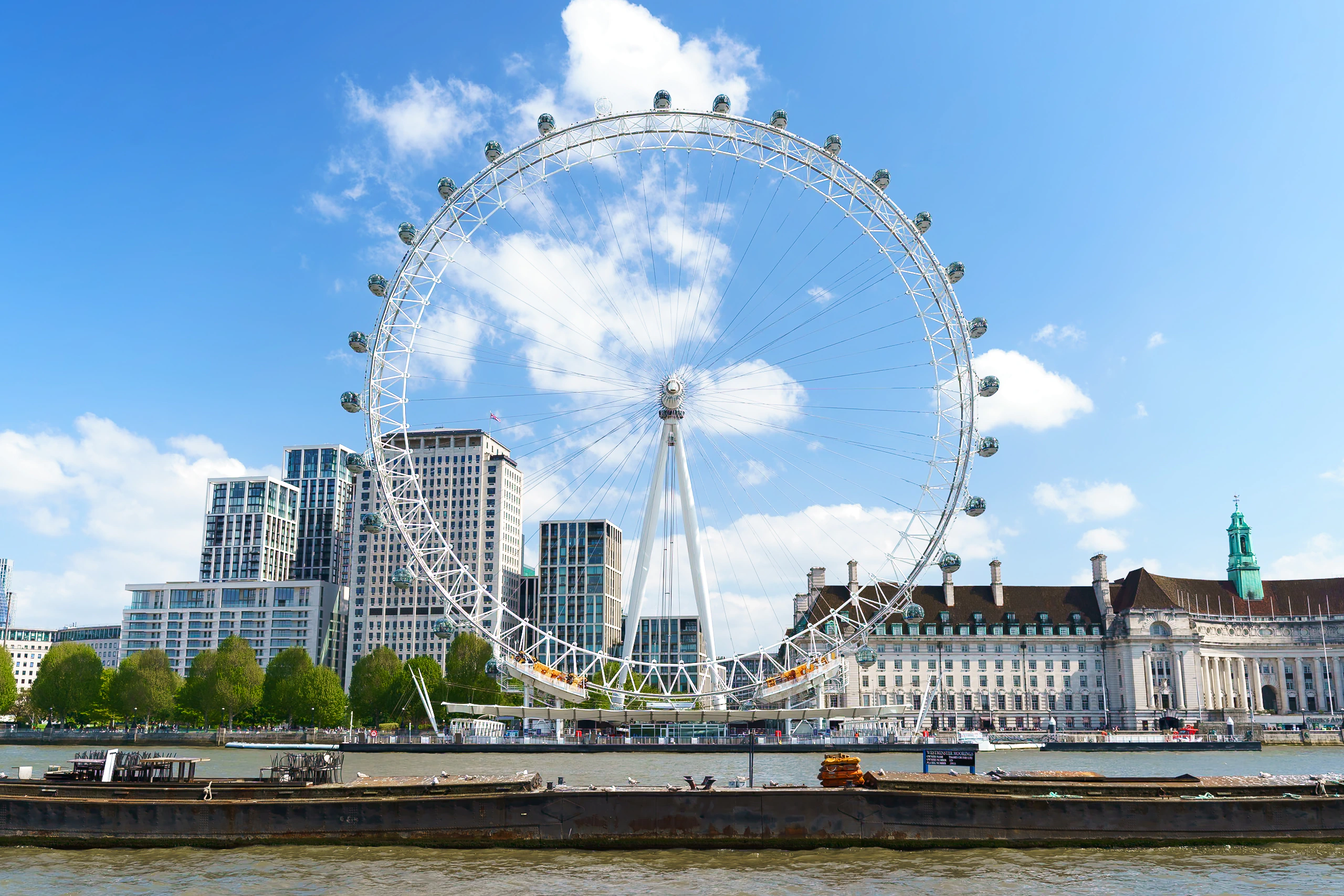 The London Eye beneath a clear blue sky across the River Thames