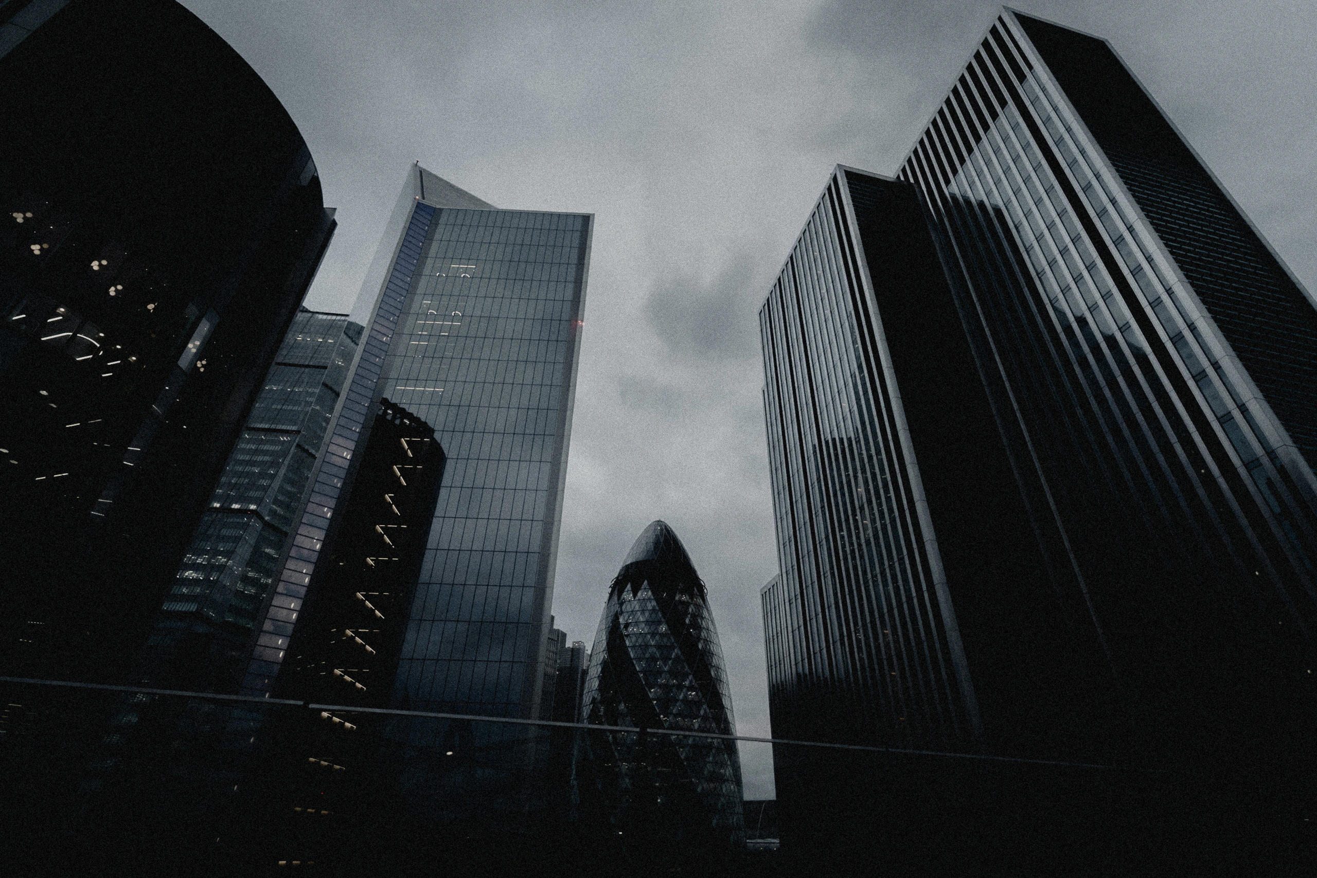 Modern London towers surrounding the Gherkin beneath cloud