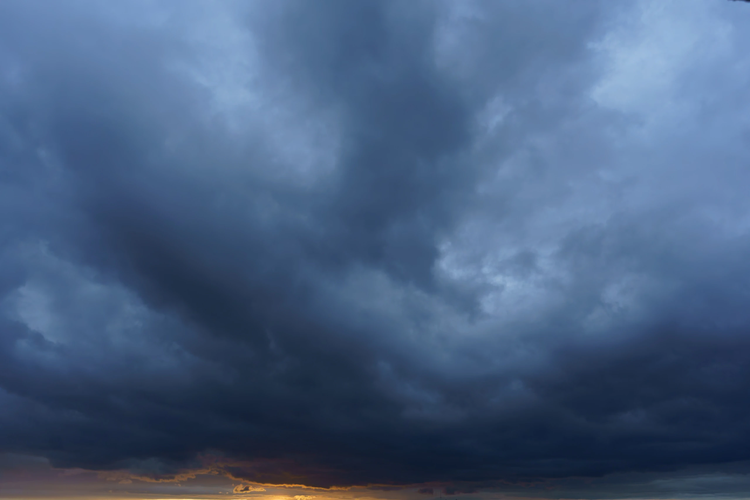 Deep blue storm cloud above a thin amber horizon