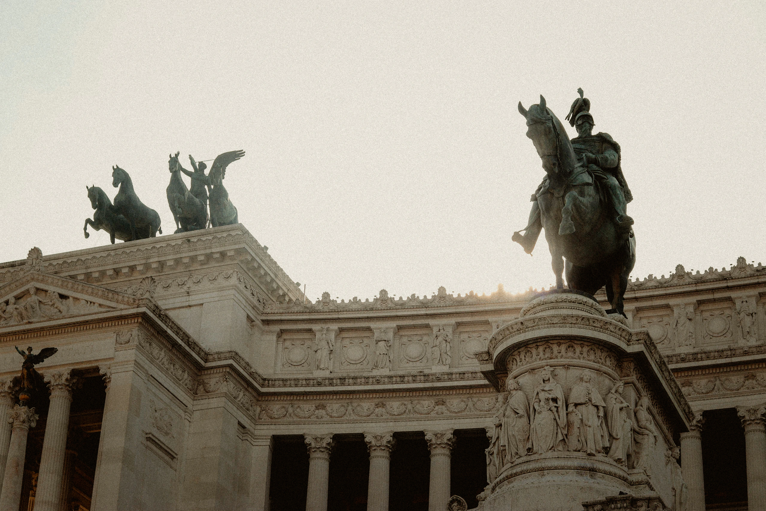 Equestrian monuments silhouetted against pale Roman light