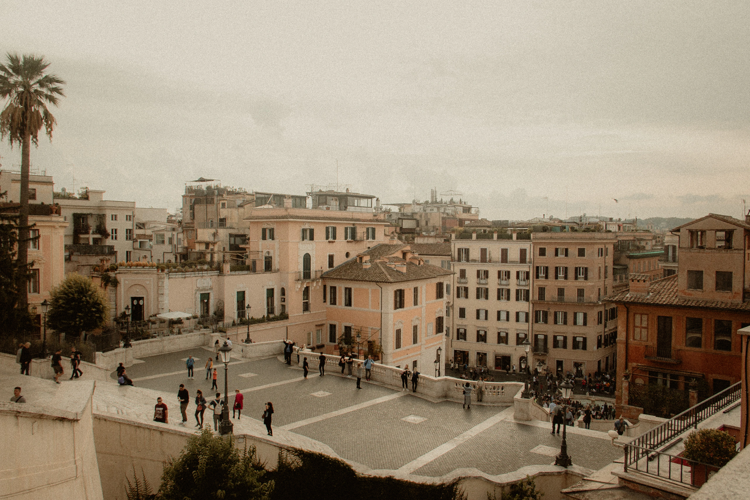 A broad view across warm Roman buildings and a busy piazza