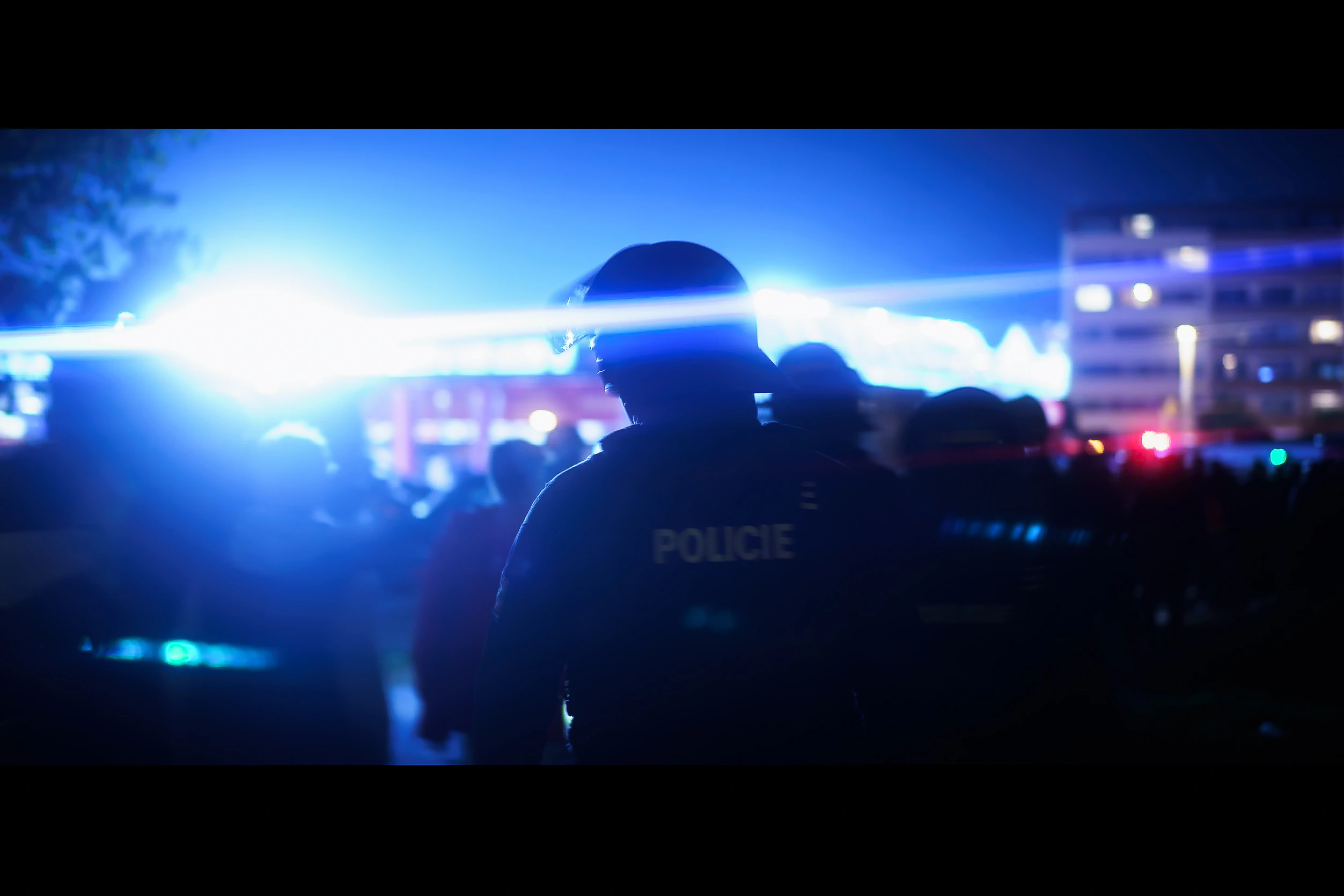 A silhouetted police officer beneath a bright horizontal line of blue emergency light