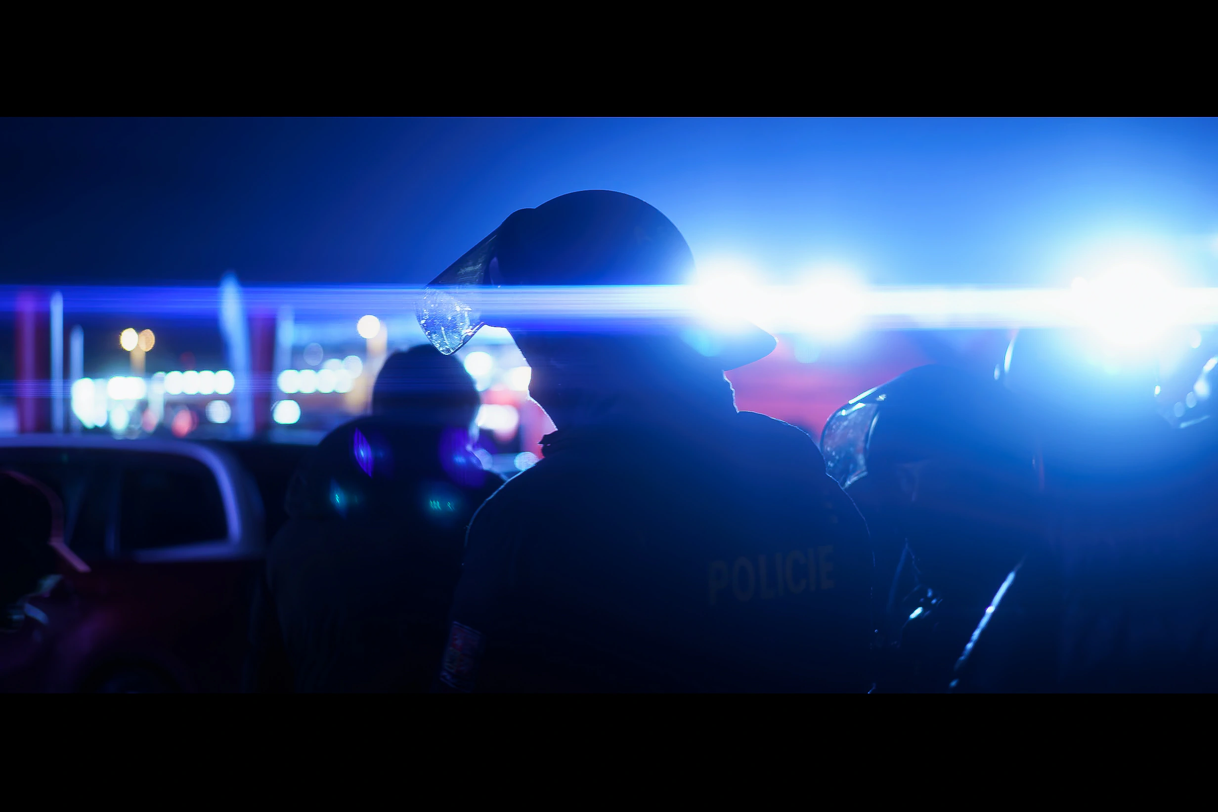 The profile of a police officer cut by a bright blue line of emergency light