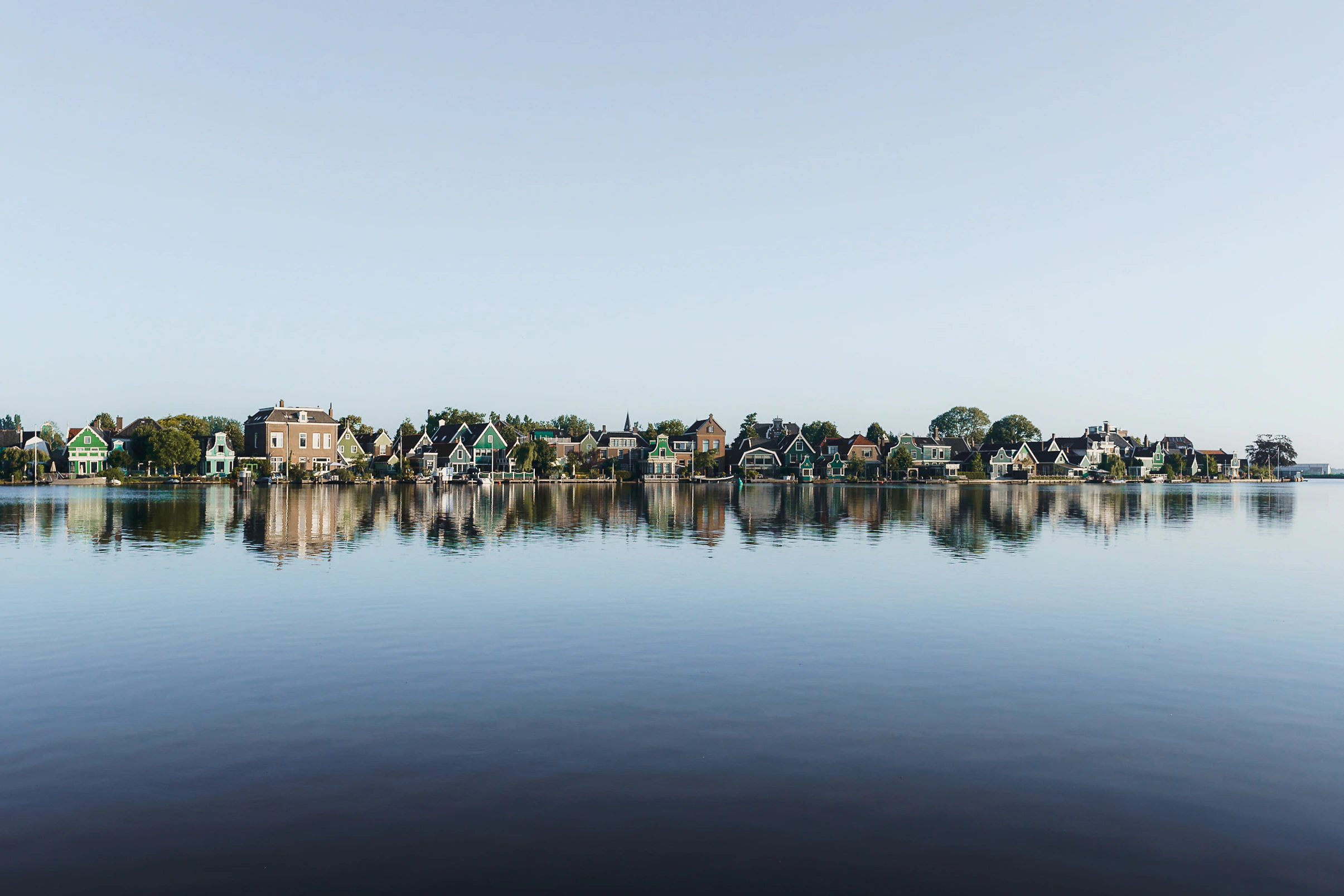 Historic houses mirrored in calm water across from Zaanse Schans