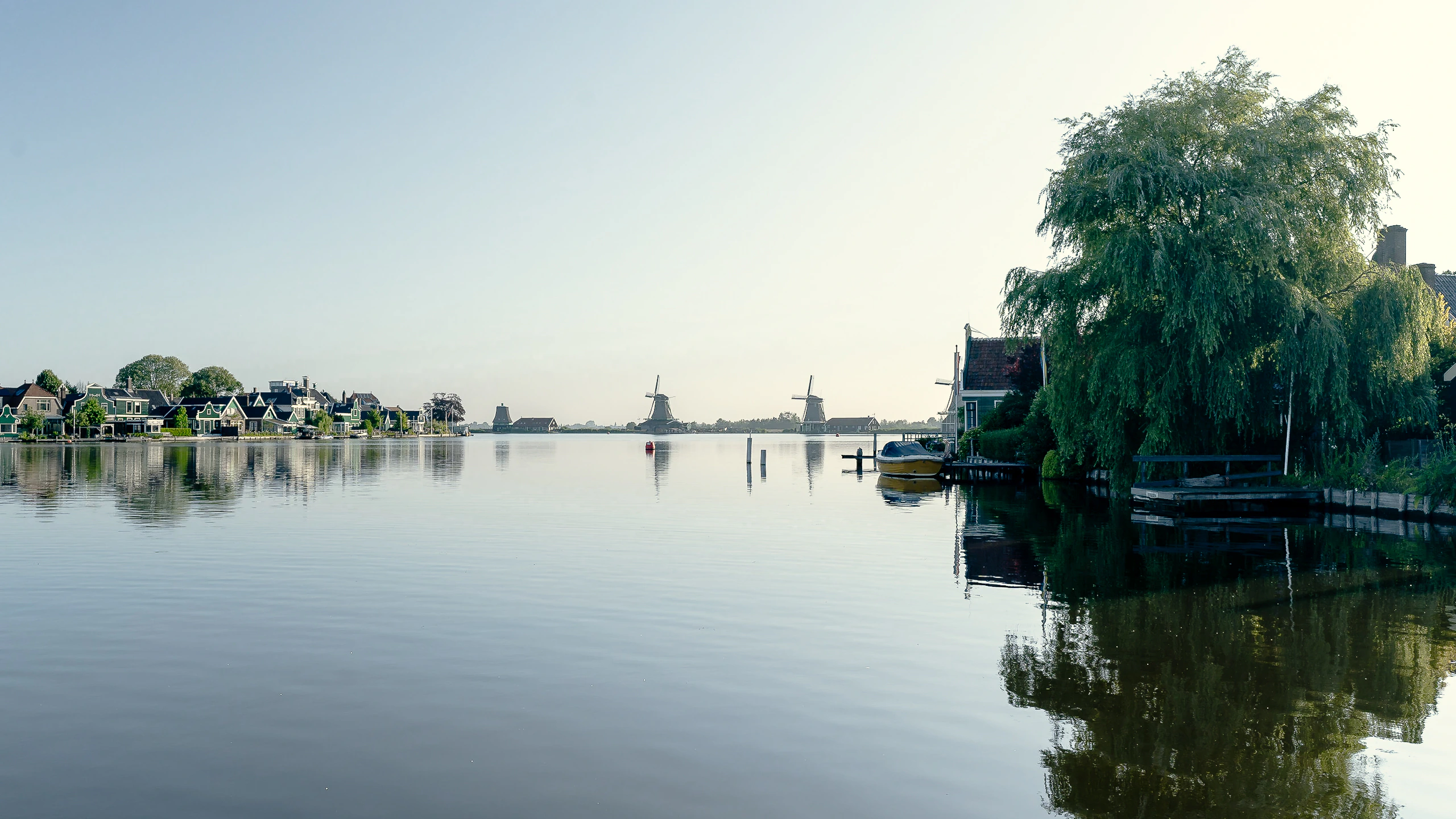 The village, distant windmills and a willow reflected across still water