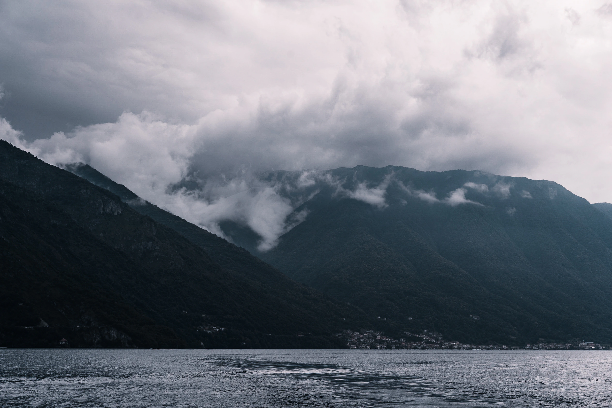 Low cloud folding into dark mountains above Lake Como