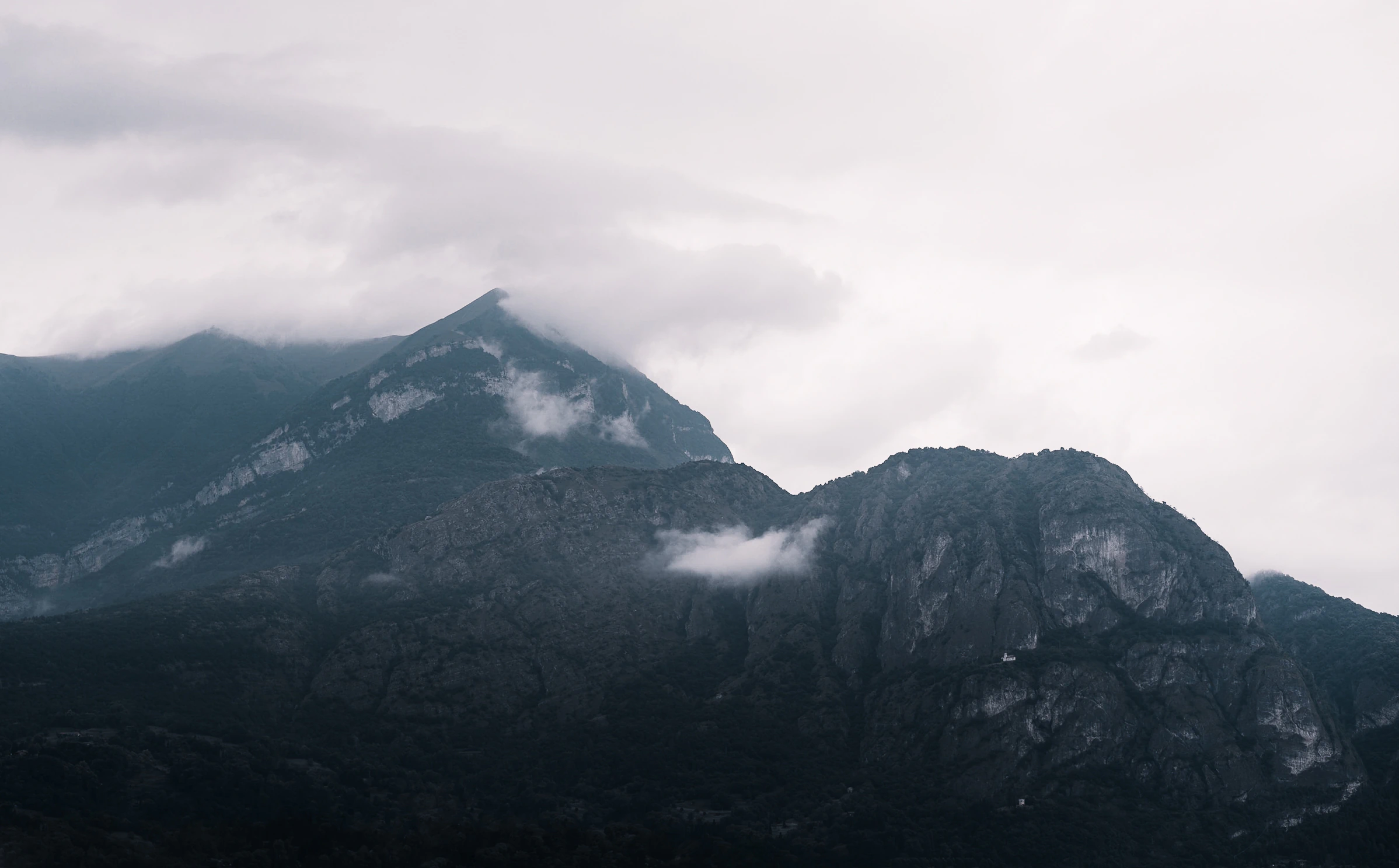 A mountain summit disappearing into ribbons of pale cloud