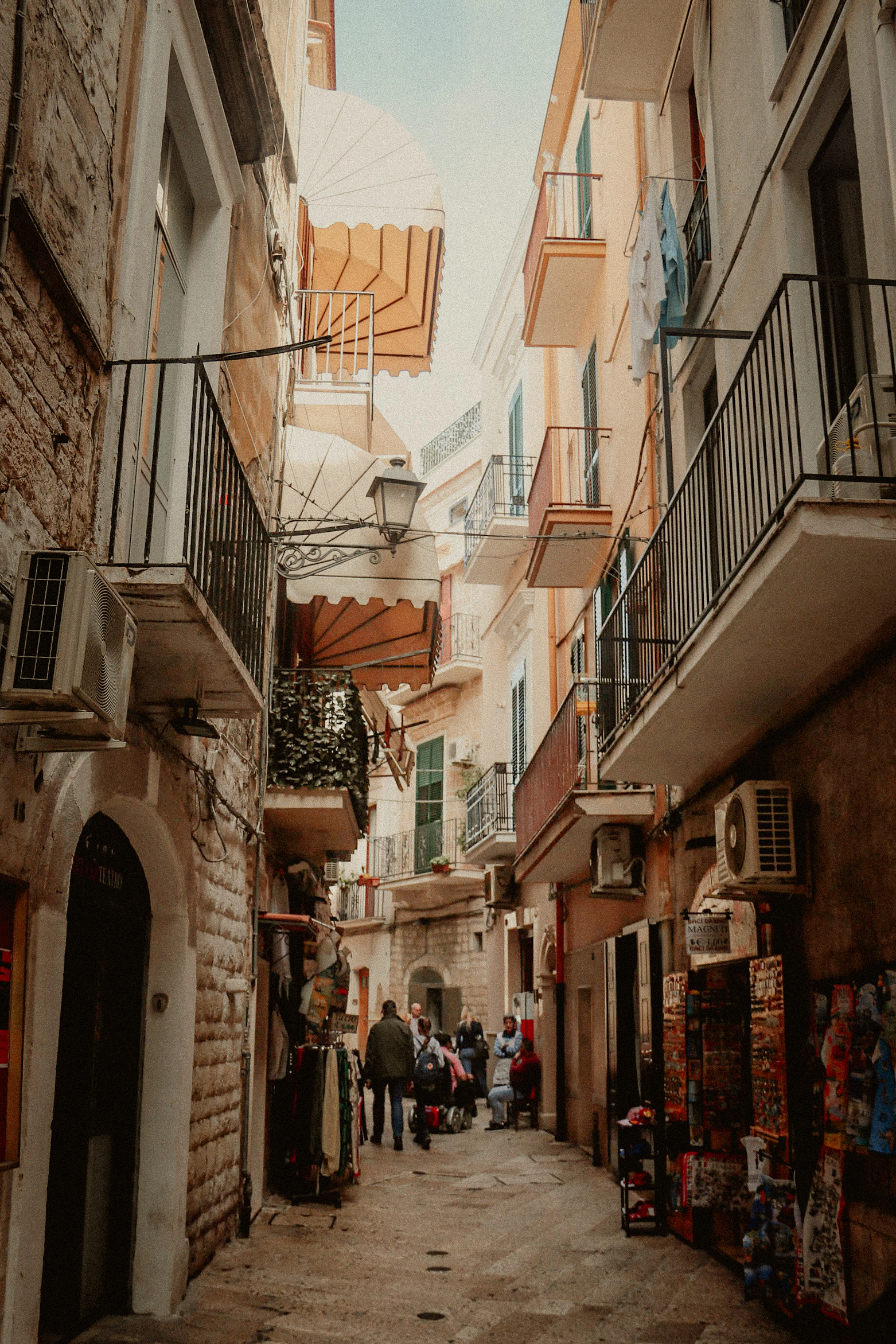 A narrow Italian street lined with balconies and awnings