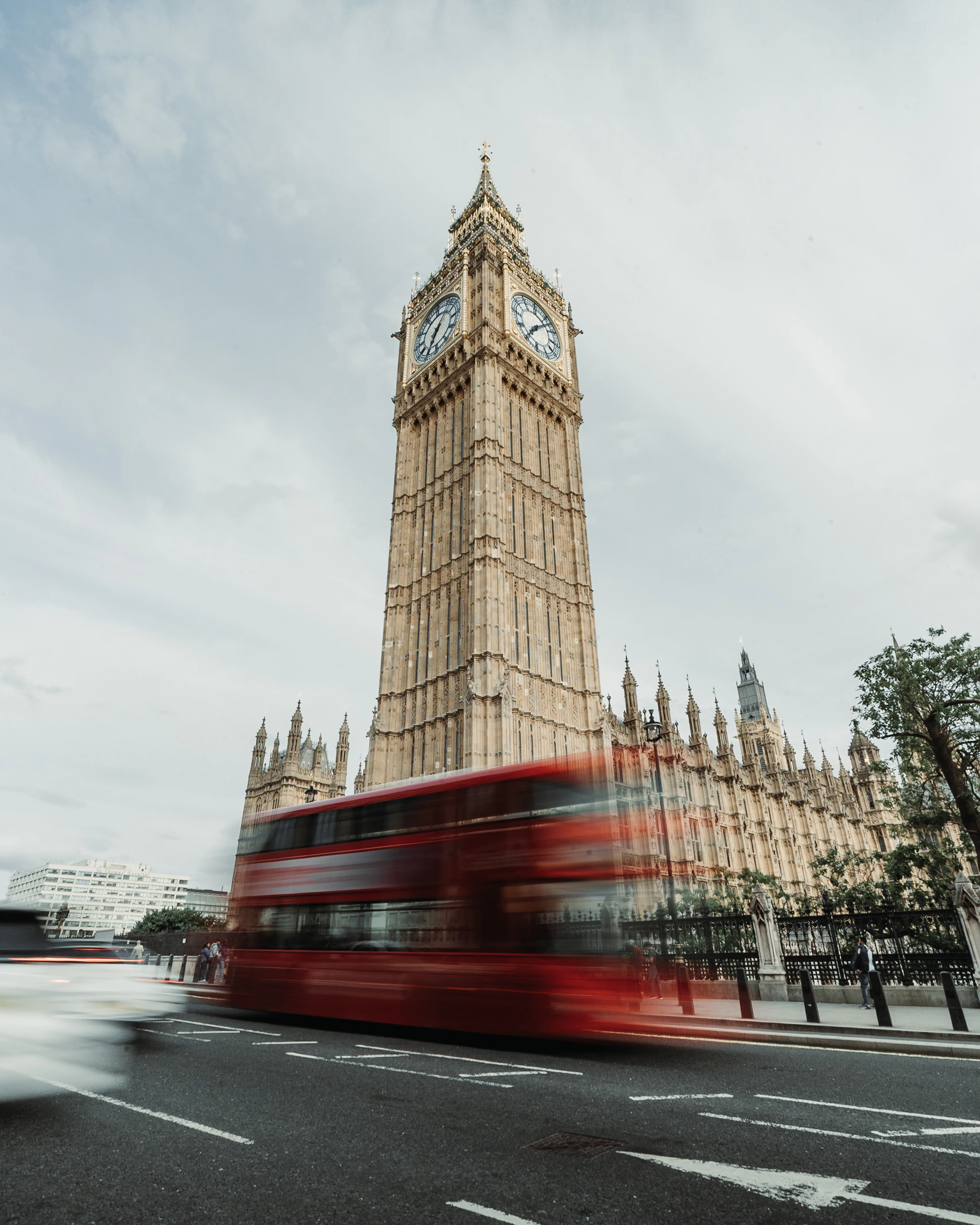 A red bus passing the Elizabeth Tower in London