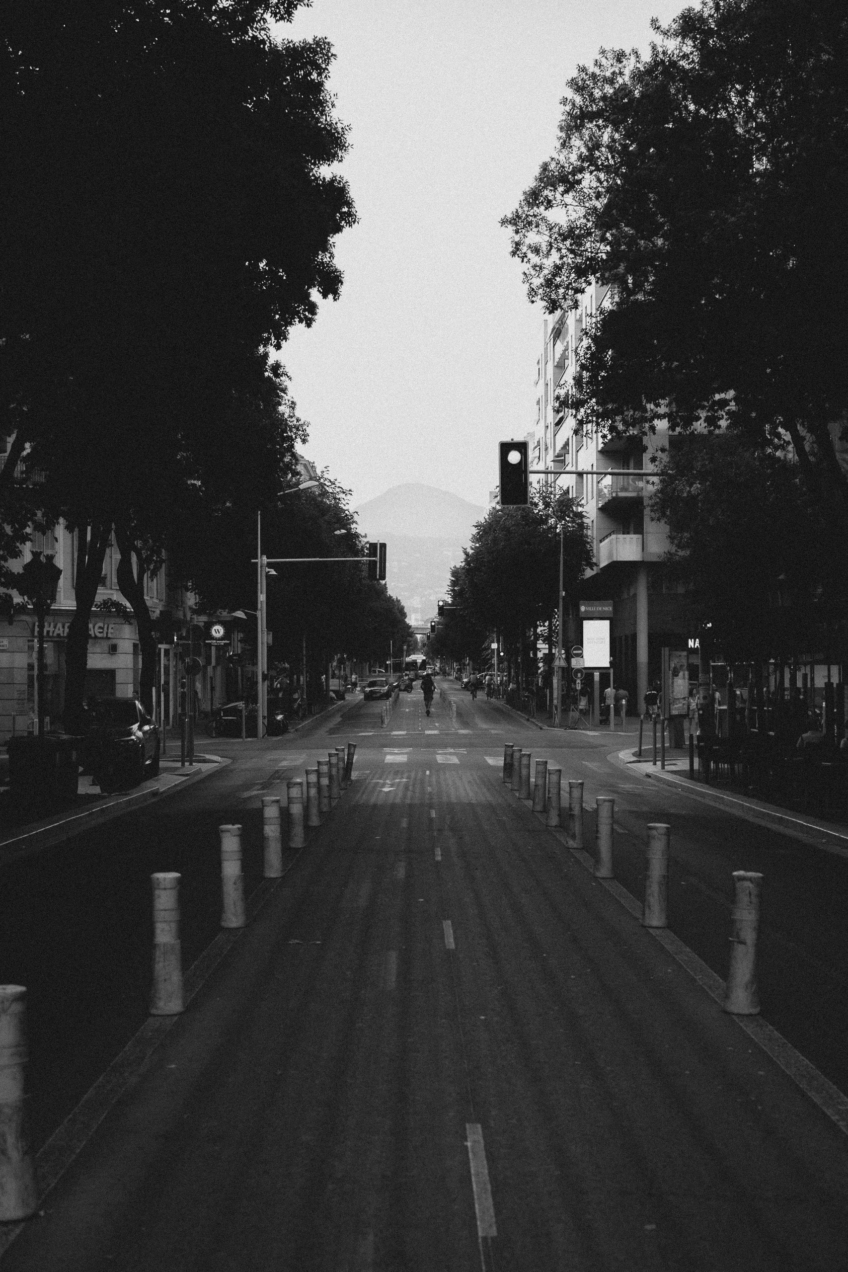 A black-and-white city avenue leading toward a distant mountain