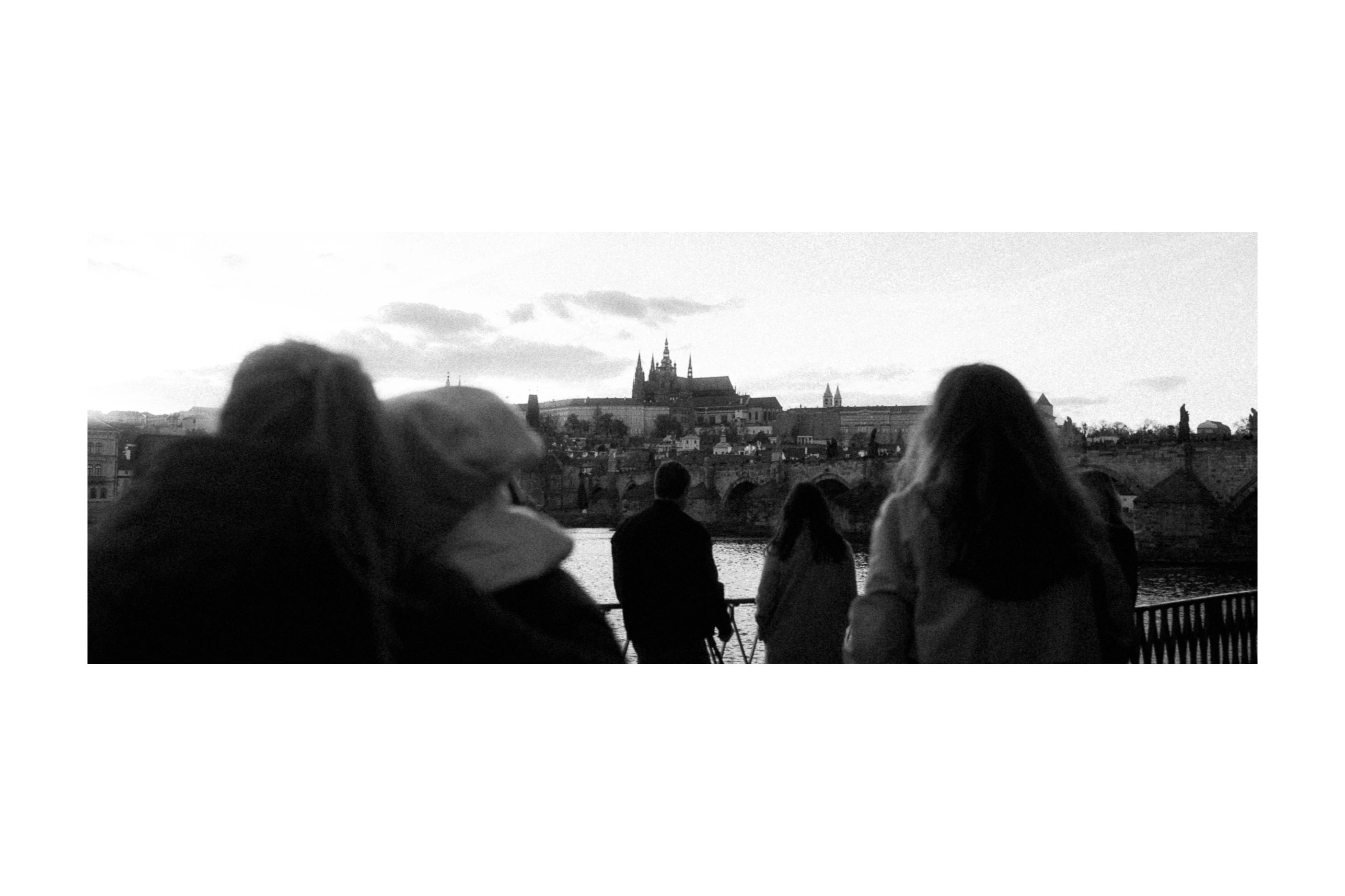 People passing beside the river with Prague Castle beyond