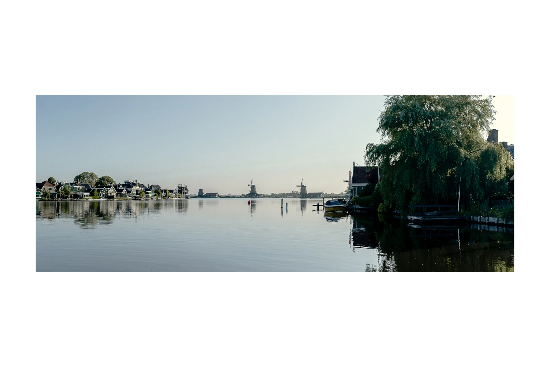Windmills and houses reflected across still water